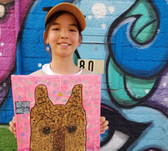 Child smiling with their artwork